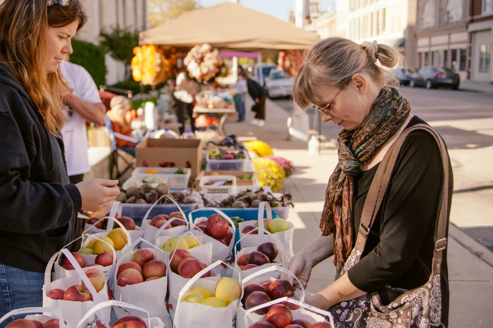 A shopper choosing produce at an outdoor market in downtown Greenville.